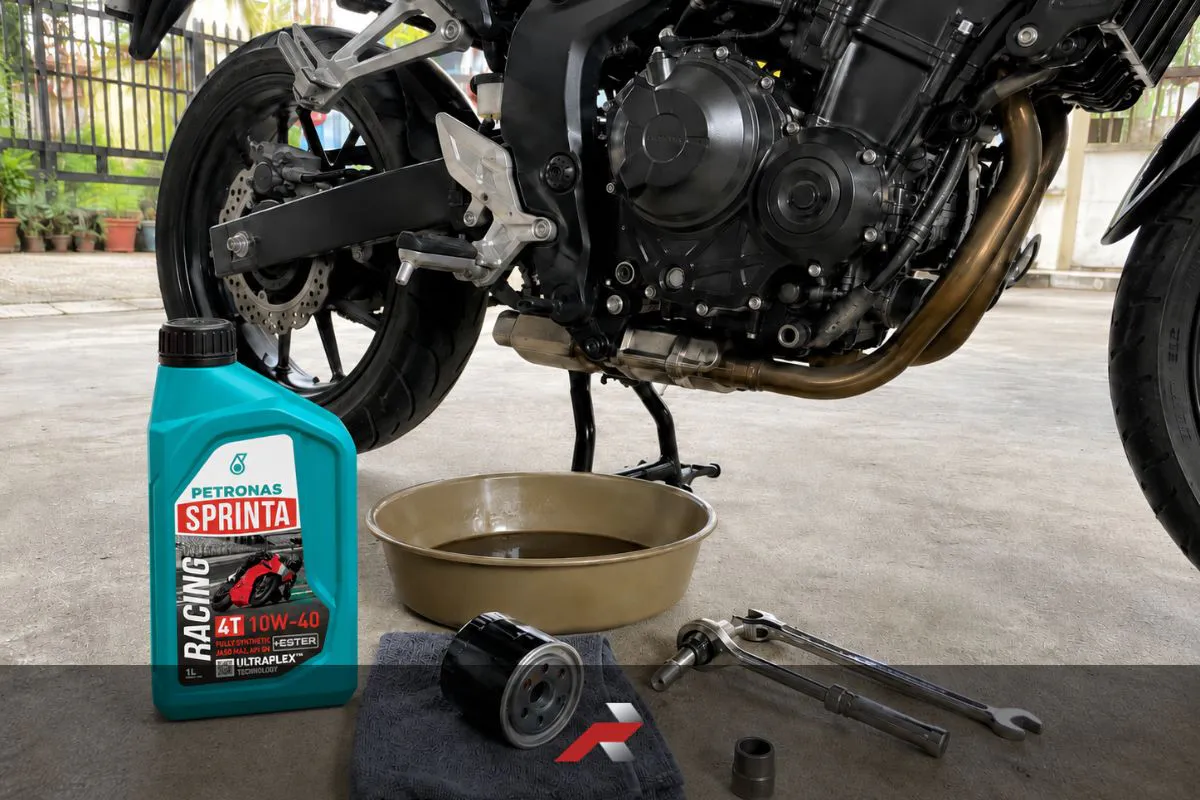 10W-40 motorcycle oil beside a motorcycle during PMS in a garage