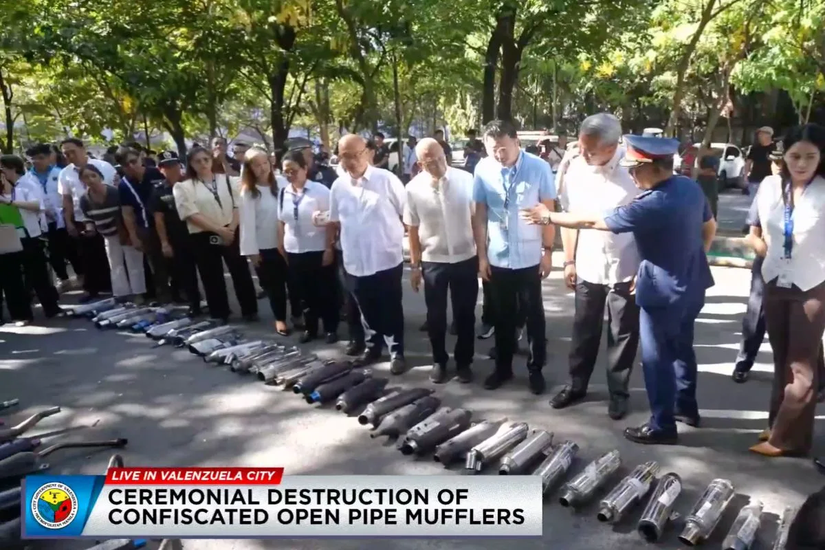 Confiscated open pipe mufflers Philippines enforcement scene in Valenzuela City showing officials inspecting seized motorcycle mufflers during a public ceremony.