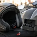 Motorcycle helmet and wireless microphone system with charging case placed on a motorcycle seat for motovlogging setup