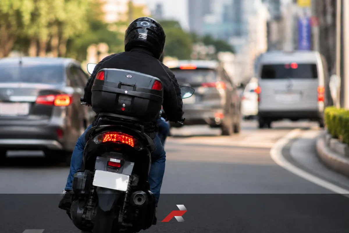 Stainless acrylic motorcycle backplates featured image showing a rider leaning slightly on a city road with a shiny rear plate area and unreadable plate number
