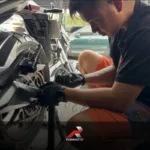 Motorcycle mechanic inspecting a chain drive for a motorcycle chain vs belt vs shaft drive comparison guide.