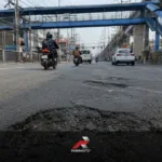 Low-angle featured image showing a large pothole on McArthur Highway in Valenzuela City, highlighting motorcycle road safety Philippines concerns